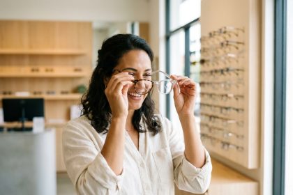 Femme comparant deux paires de lunettes dans une boutique d'optique moderne