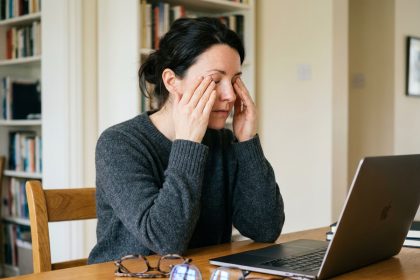 Femme fatiguée des yeux comparant plusieurs montures de lunettes sur son bureau à domicile